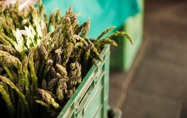 Asparagi verdi organici in cassa di plastica da vendere su una bancarella del mercato