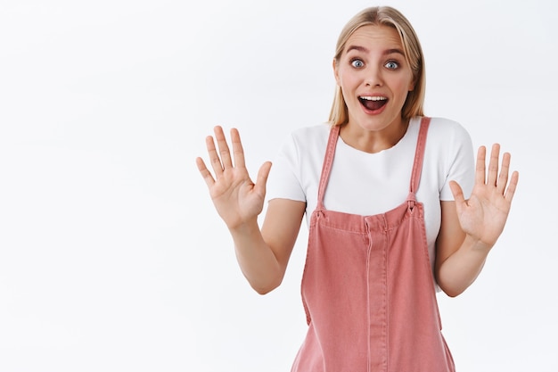 Aspetta, non ci crederai mai. Stupita, eccitata, bella donna bionda caucasica che racconta notizie calde estremamente fantastiche, alzando le mani in stop motion e sorridendo divertito, stand sfondo bianco