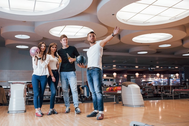 Aspettando l'inizio del gioco. I giovani amici allegri si divertono al bowling durante i fine settimana