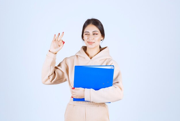 Assistente con una cartella blu che mostra il segno di godimento