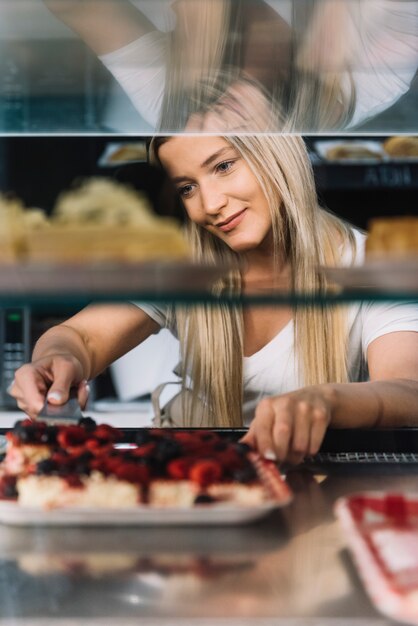 Assistente di negozio che prende la pasticceria
