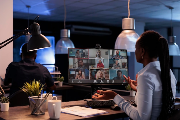 Assistente esecutivo che parla con il team aziendale in videochiamata remota, chatta in teleconferenza online con i colleghi. Utilizzo di computer e webcam per partecipare a riunioni di telelavoro in videoconferenza.