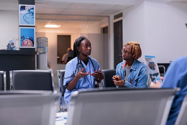 Assistente medico che consulta donna in clinica, parlando di malattia e assistenza sanitaria all'appuntamento per la visita di controllo. Infermiera e paziente che fanno consultazione in sala d'attesa.