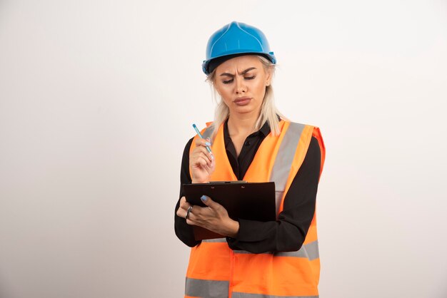 Assistente tecnico femminile che controlla le note su priorità bassa bianca. Foto di alta qualità