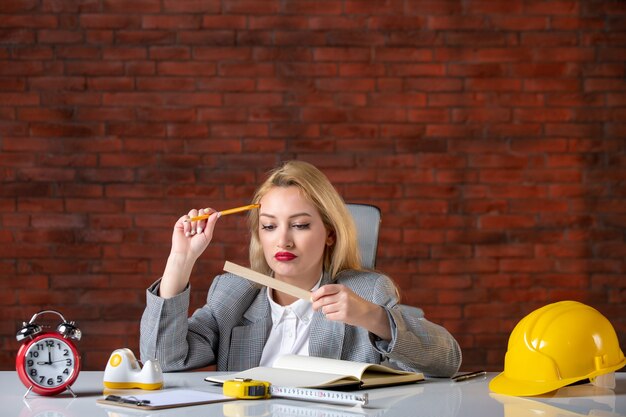 Assistente tecnico femminile di vista frontale che si siede dietro il suo posto di lavoro