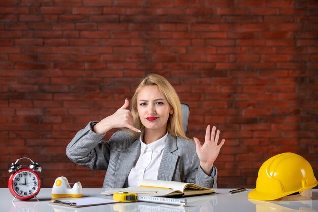 Assistente tecnico femminile di vista frontale che si siede dietro il suo posto di lavoro