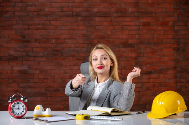 Assistente tecnico femminile di vista frontale che si siede dietro il suo posto di lavoro