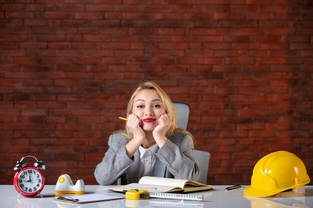 Assistente tecnico femminile di vista frontale che si siede dietro il suo posto di lavoro