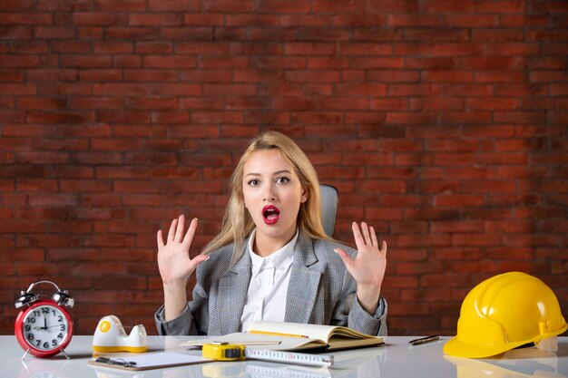 Assistente tecnico femminile di vista frontale che si siede dietro il suo posto di lavoro