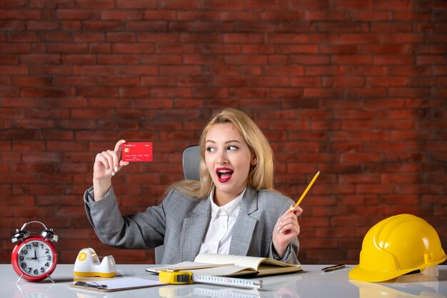 Assistente tecnico femminile di vista frontale che si siede dietro il suo posto di lavoro