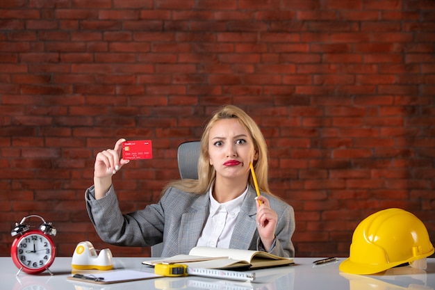 Assistente tecnico femminile di vista frontale che si siede dietro il suo posto di lavoro