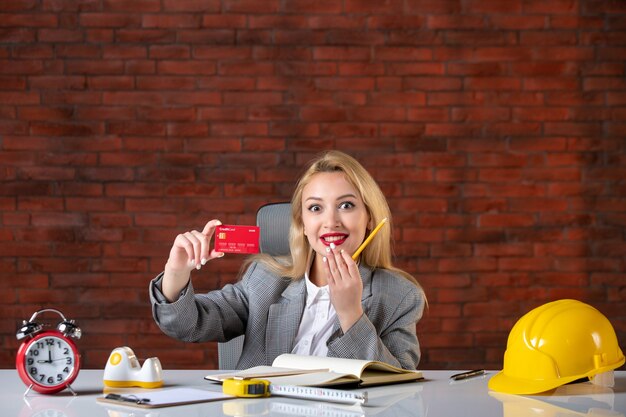 Assistente tecnico femminile di vista frontale che si siede dietro il suo posto di lavoro