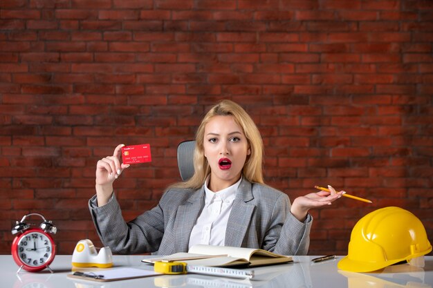 Assistente tecnico femminile di vista frontale che si siede dietro il suo posto di lavoro