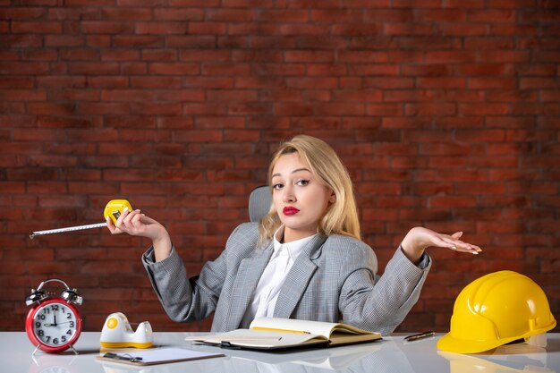 Assistente tecnico femminile di vista frontale che si siede dietro il suo posto di lavoro