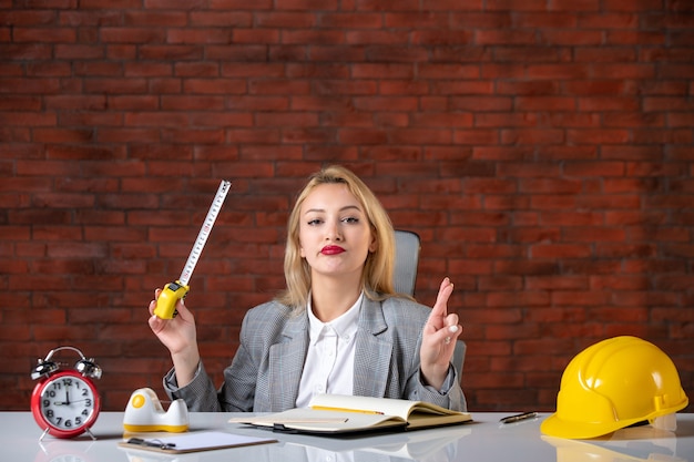 Assistente tecnico femminile di vista frontale che si siede dietro il suo posto di lavoro