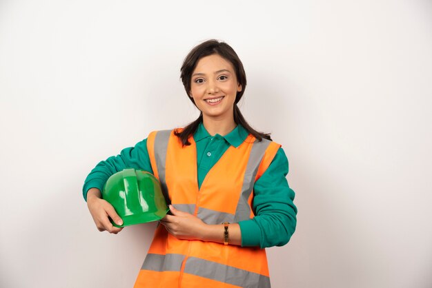 Assistente tecnico femminile sorridente che tiene un casco su priorità bassa bianca.