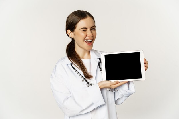 Assistenza medica online appuntamento remoto sorridente bella donna medico che mostra lo schermo del tablet digitale ...