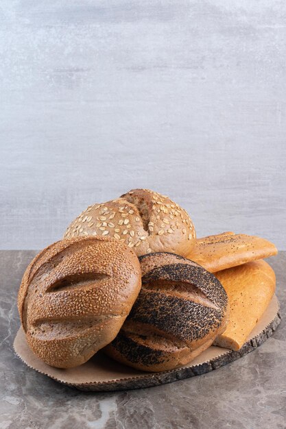 Assortimento accatastato di diversi tipi di pane su sfondo marmo. Foto di alta qualità