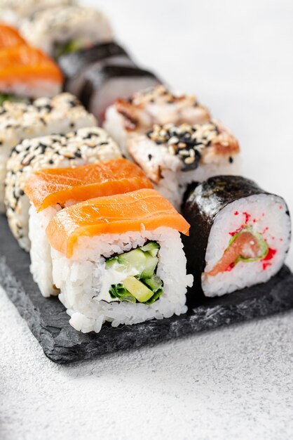 Assortimento dei rotoli di sushi di maki del primo piano sull'ardesia