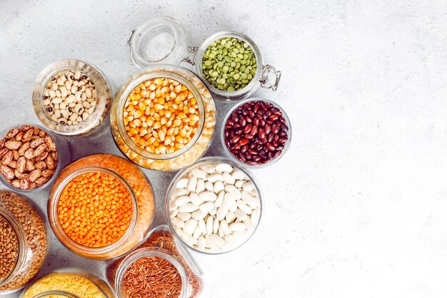 Assortimento di legumi e fagioli in diverse ciotole su pietra chiara. Vista dall'alto. Cibo proteico vegano sano.