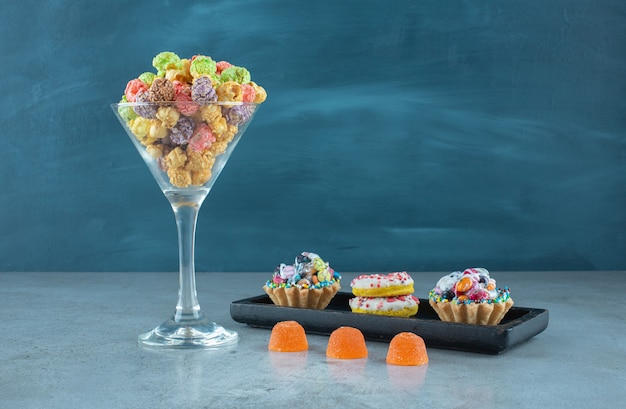 Assortimento di snack con ciambelle, popcorn, cupcakes e caramelle di gelatina sulla superficie in marmo