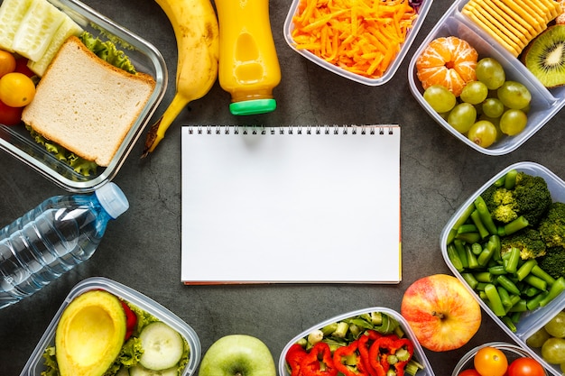 Assortimento di vista dall'alto di alimenti in lotti cucinati con taccuino vuoto