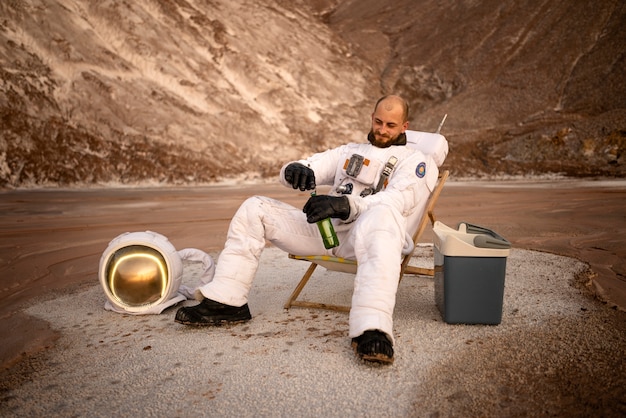 Astronauta maschio apre una birra durante una missione spaziale su un pianeta sconosciuto