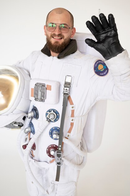 Astronauta maschio che saluta e tiene il casco