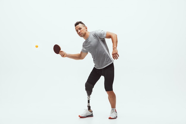 Atleta con disabilità o amputato isolato su bianco. Giocatore di tennis maschile professionista con allenamento per protesi delle gambe