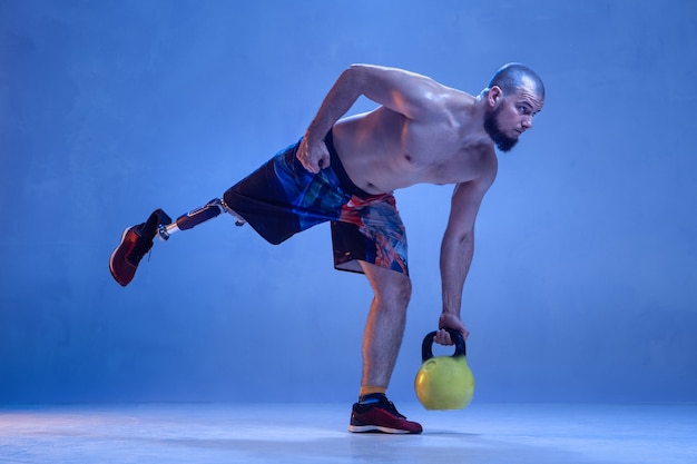 Atleta con disabilità o amputato isolato sulla parete blu.