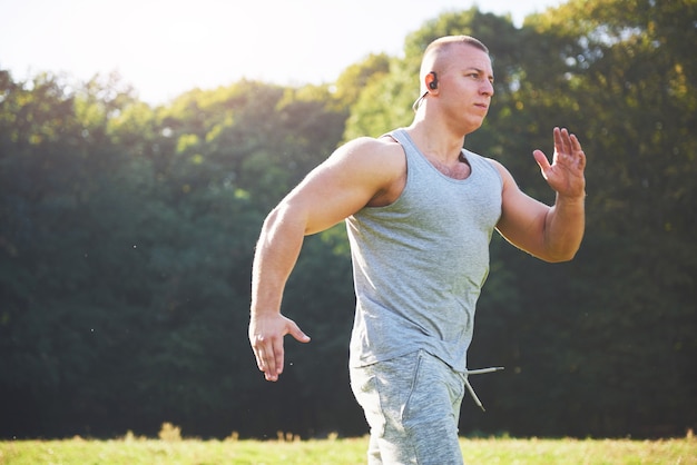 Atleta dell'uomo di forma fisica che pareggia nella natura durante il tramonto.