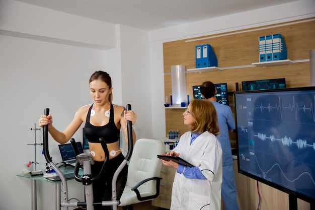 Atleta femminile che fa uno sforzo fisico sullo stepper e il dottore la segue. Laboratorio sportivo