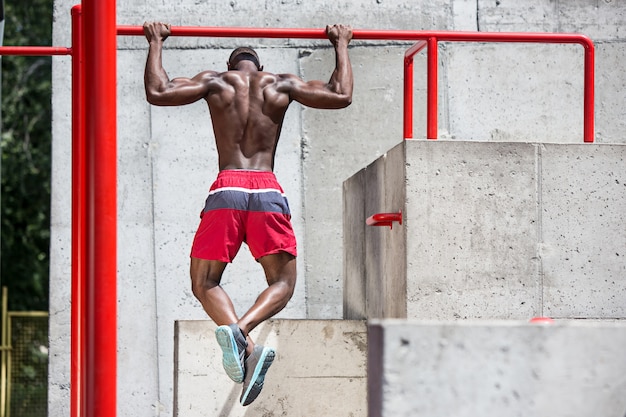 atleta in forma facendo esercizi allo stadio. Uomo afro o afroamericano all'aperto in città