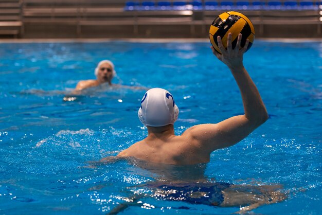 Atleta maschio che gioca pallanuoto in piscina coperta