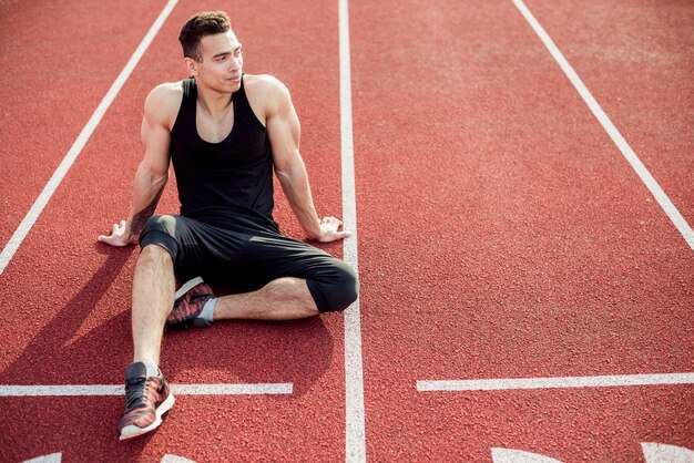 Atleta maschio che si rilassa sulla pista di corsa rossa