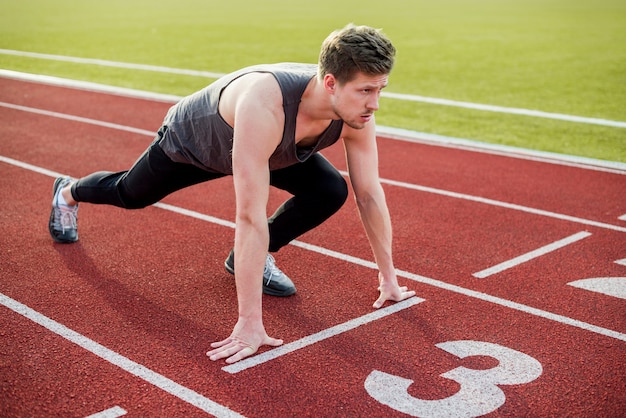 Atleta maschio pronto per iniziare la gara sulla pista di atletica