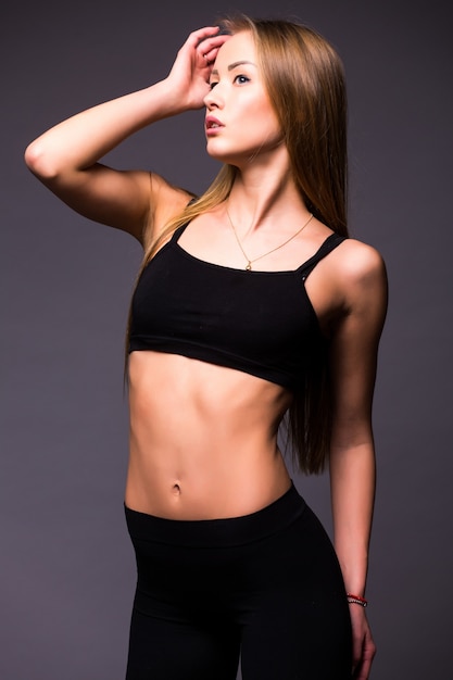 Atleta muscoloso giovane donna in piedi sul muro grigio