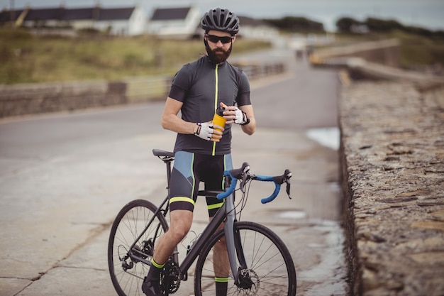 Atleta rinfrescante dalla bottiglia mentre va in bicicletta