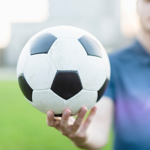 Atleta sfocato che mostra il pallone da calcio