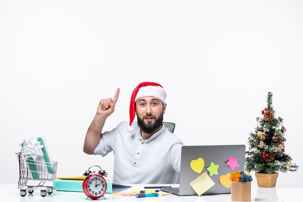 Atmosfera natalizia con un giovane adulto confuso con il cappello di babbo natale che controlla le sue e-mail che puntano sopra nell'ufficio