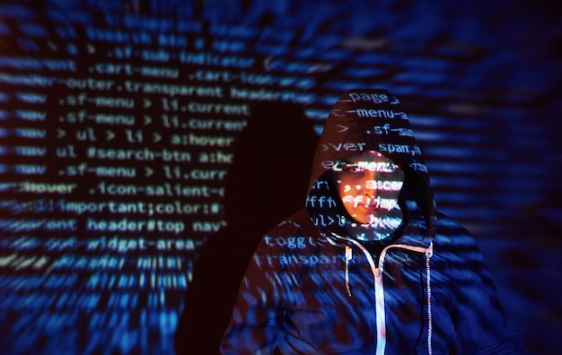 Attacco informatico con hacker incappucciato irriconoscibile utilizzando la realtà virtuale, effetto glitch digitale