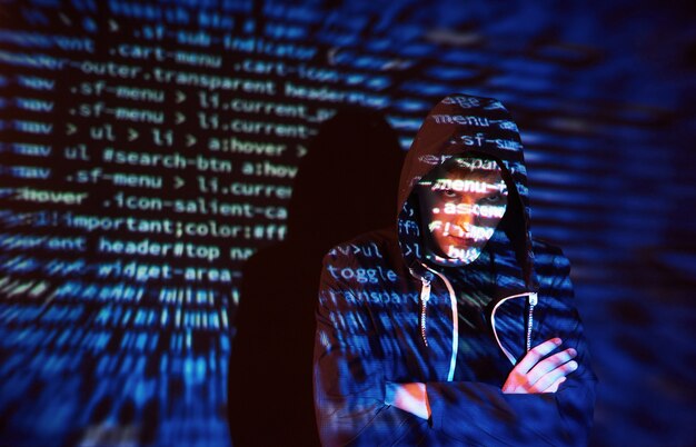 Attacco informatico con hacker incappucciato irriconoscibile utilizzando la realtà virtuale, effetto glitch digitale