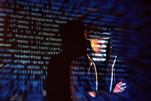 Attacco informatico con hacker incappucciato irriconoscibile utilizzando la realtà virtuale, effetto glitch digitale