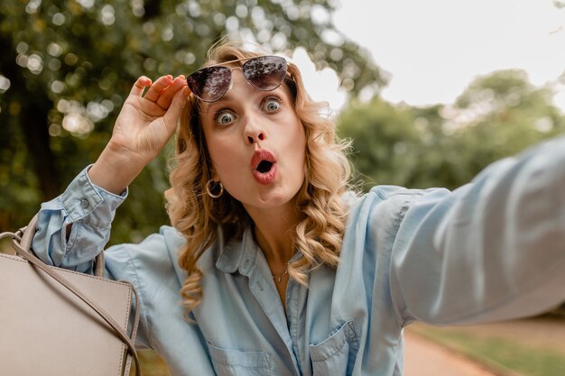 Attraente bionda donna divertente surpried in abito estivo che cattura foto selfie sul telefono