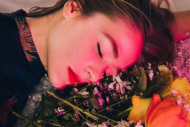 Attraente donna affascinante sdraiata con bouquet di fiori in rosa