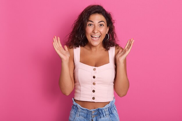 Attraente donna con le mani aperte, in piedi stupita o sorpresa, abito alla moda dresse, esprime felicità