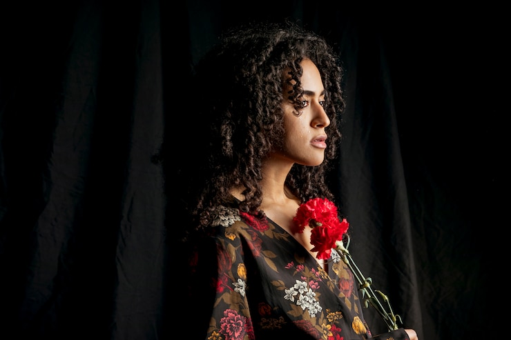 Foto gratuito attraente donna etnica con fiori rossi nel buio