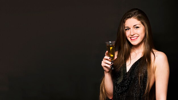 Attraente donna felice in panno di sera con un bicchiere di bevanda