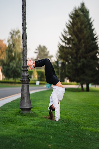 Attraente donna magra che fa un backbend mentre mostra una capriola.