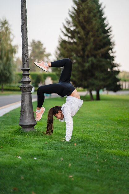 Attraente donna magra che fa un backbend mentre mostra una capriola.